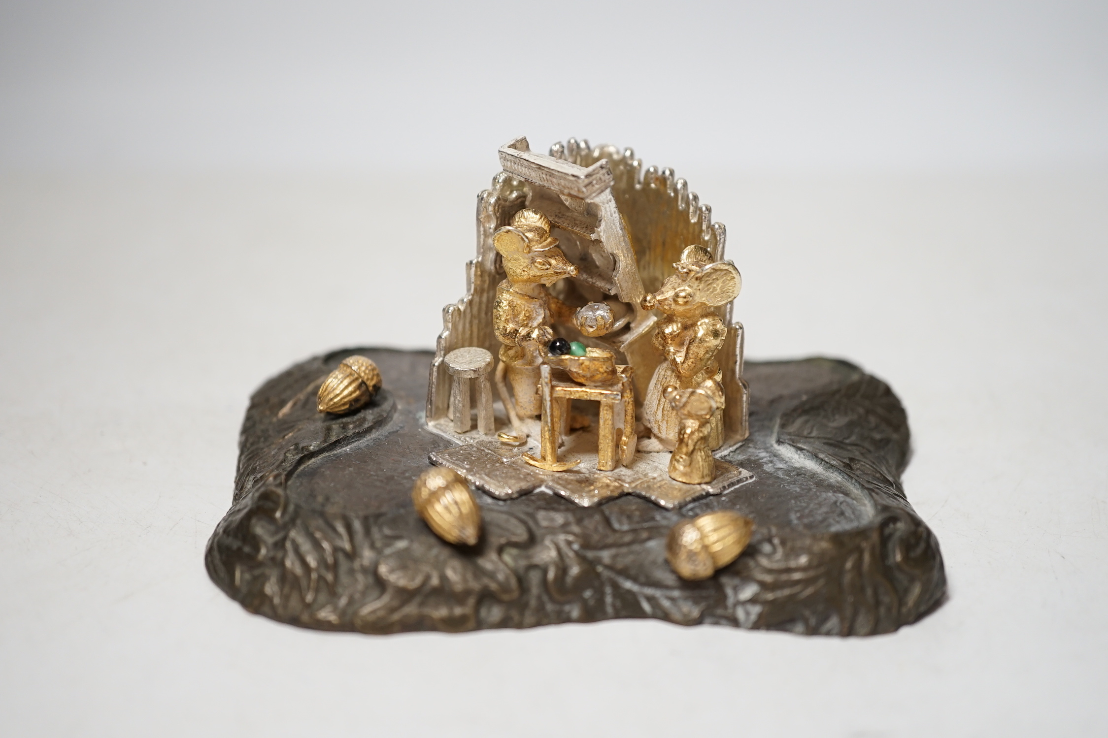 A limited edition Elizabeth II parcel gilt silver and base metal model by Christopher Nigel Lawrence, depicting pixies upon a tree stump, opening to reveal mice in kitchen scene, numbered 20/250, height 11.2cm.